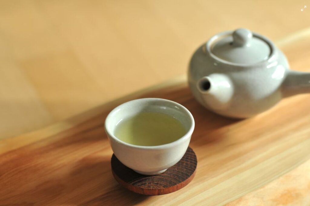 Green tea leaves with steam rising from a teacup